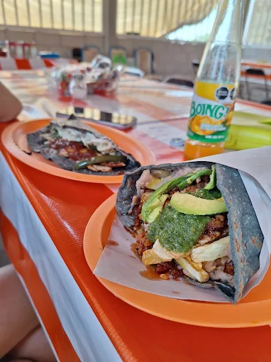 Gordita de maíz azul abierta con guisado, aguacate y salsa verde